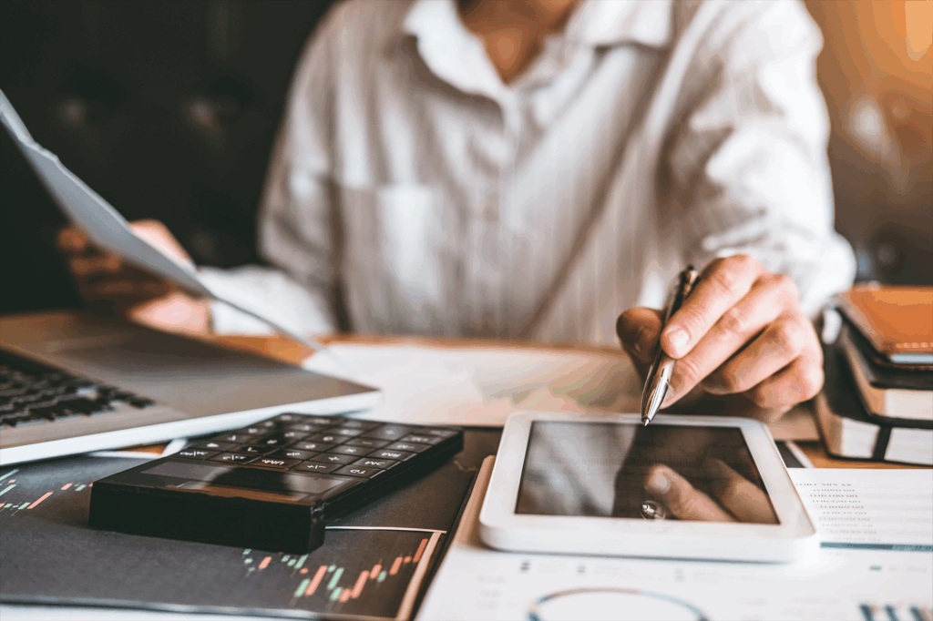 Mulher analisando documentos e mexendo no celular