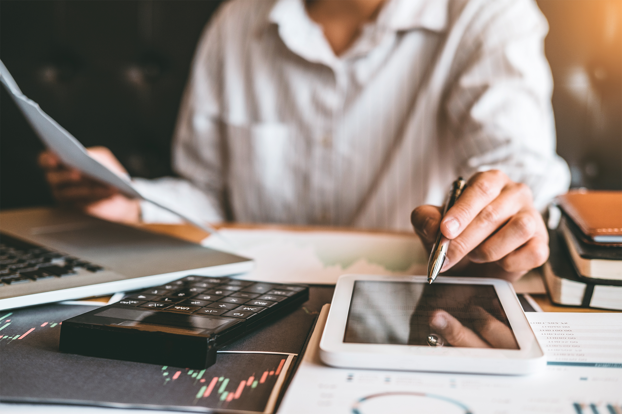 Mulher analisando documentos e mexendo no celular