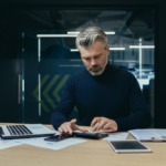 Analista de negócios financeiro de pensamento sério trabalhando com documentos dentro do escritório adulto maduro