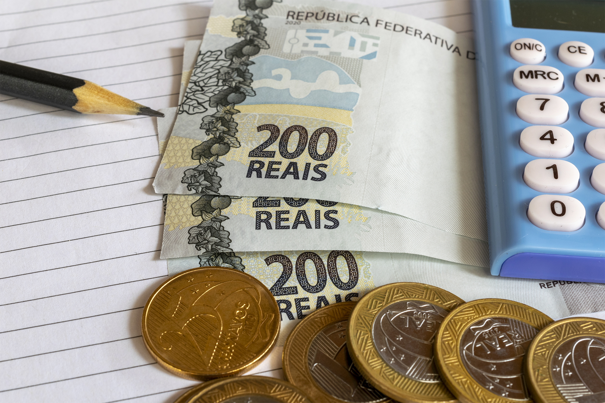Calculadora de moedas e notas de dinheiro brasileiro e lápis na mesa de atendimento emergencial