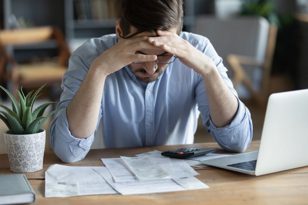 Homem deprimido verificando contas ansiedade sobre dívida ou falência problema financeiro dívida bancária ou falta de dinheiro infeliz frustrado jovem homem sentado na mesa de trabalho com laptop e calculadora