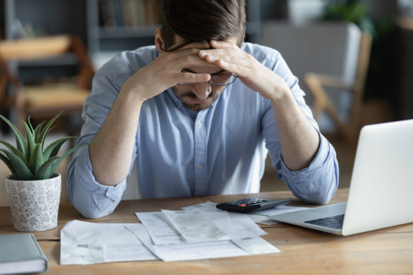 Homem deprimido verificando contas ansiedade sobre dívida ou falência problema financeiro dívida bancária ou falta de dinheiro infeliz frustrado jovem homem sentado na mesa de trabalho com laptop e calculadora