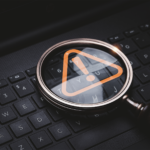 Lupa de vidro com sinal de aviso de advertência de triângulo vermelho no teclado de computador portátil para erro de notificação e conceito de exclamação de tecnologia de manutenção
