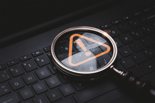 Lupa de vidro com sinal de aviso de advertência de triângulo vermelho no teclado de computador portátil para erro de notificação e conceito de exclamação de tecnologia de manutenção
