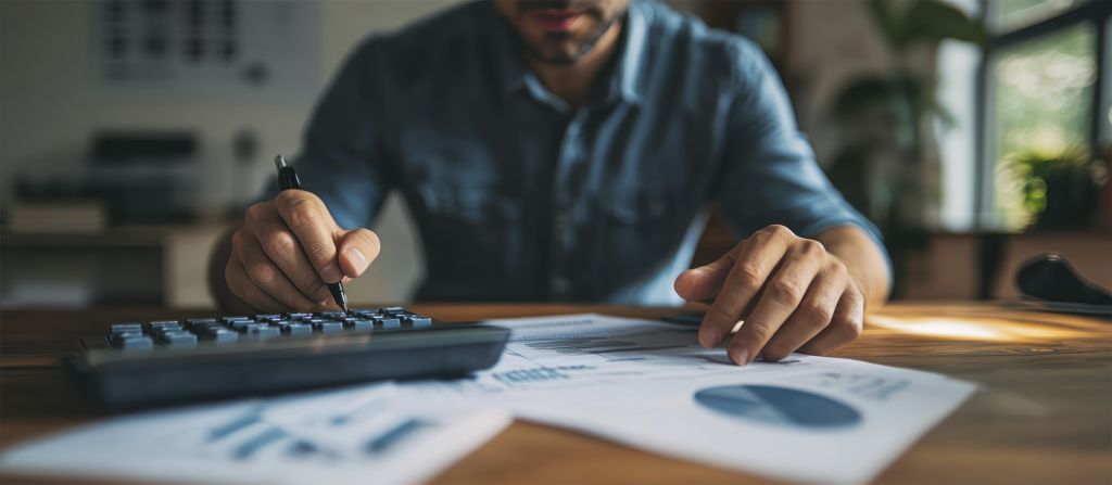 Close-up de uma mão de um empresário39 usando uma calculadora e revisando gráficos financeiros