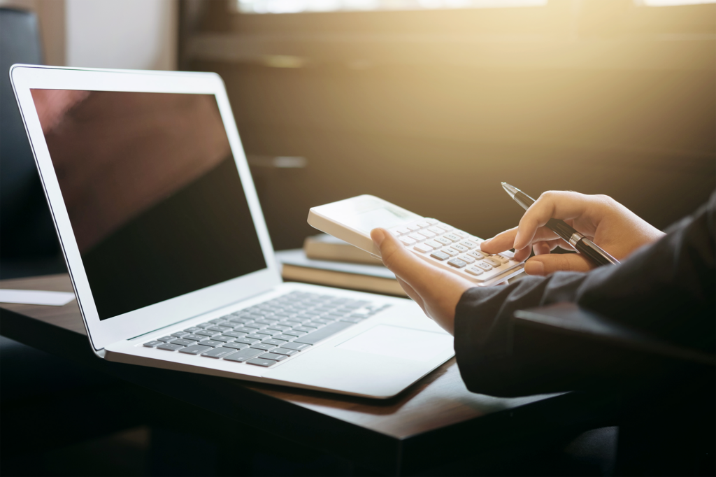 Mãos cortadas de uma mulher de negócios usando uma calculadora por laptop na mesa do escritório
