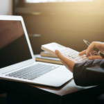Mãos cortadas de uma mulher de negócios usando uma calculadora por laptop na mesa do escritório
