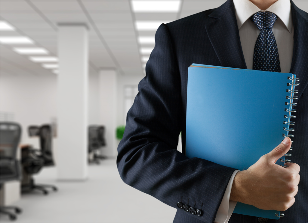 Empresário segurando caderno com capa azul contra seu corpo